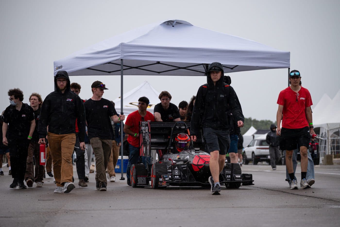 The team walking the car up to grid at Michigan International Speedway in the rain.