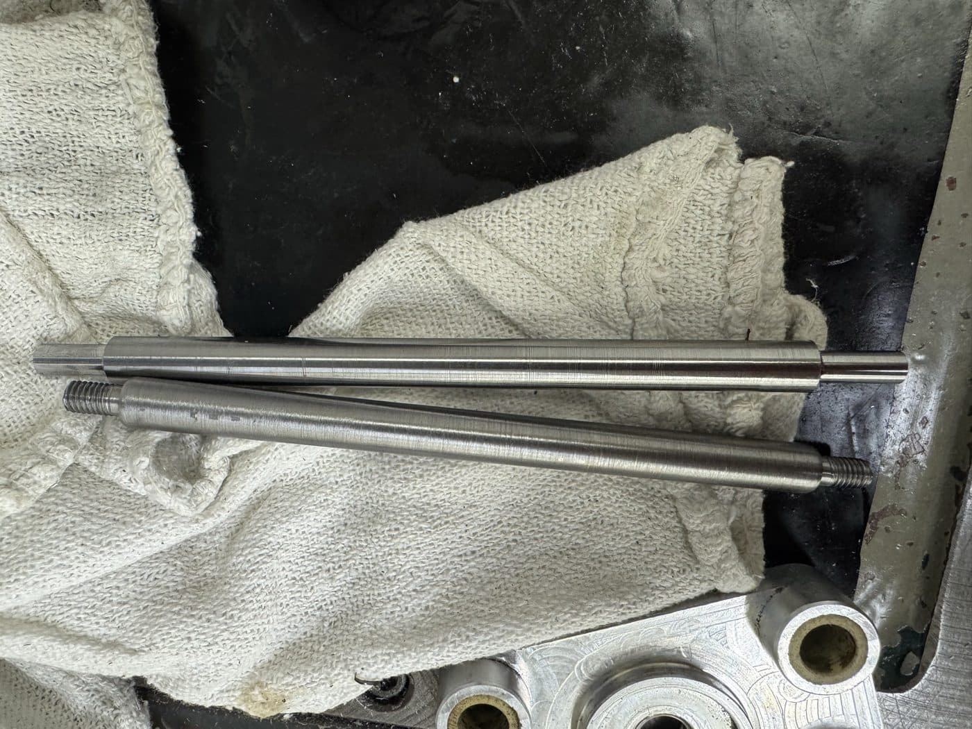 Turned steel tie-rod shafts with threaded ends, cut on the manual lathe and matched as a pair.