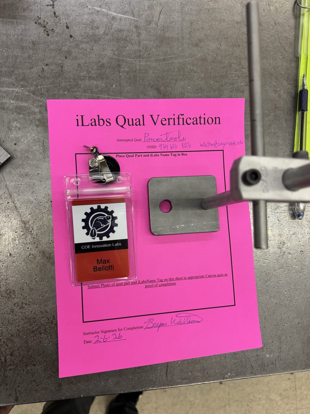 Signed iLabs power tools qualification sheet with a cut and drilled steel plate.