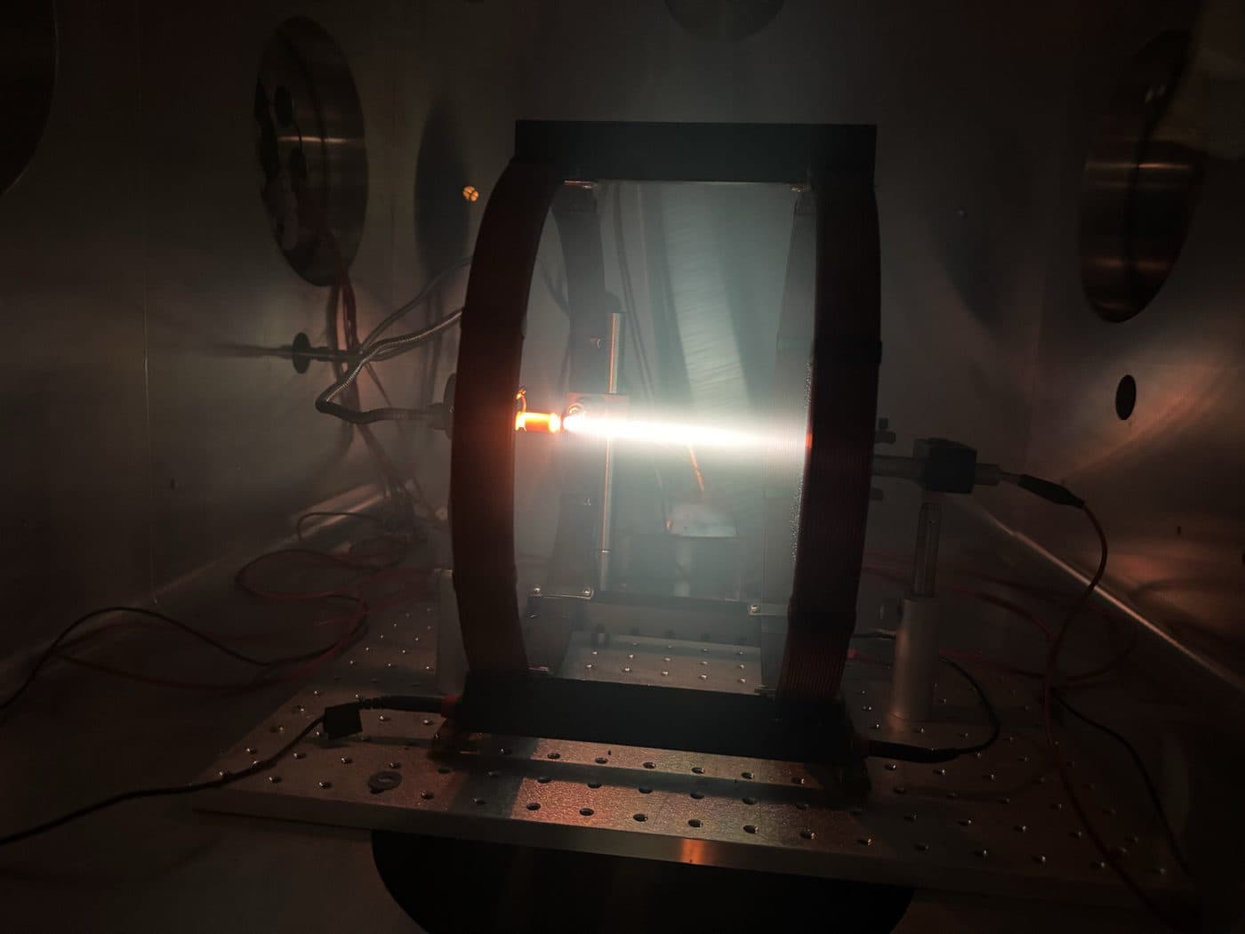 A plasma discharge running inside one of the lab's vacuum chambers, between the Helmholtz coils on the optical breadboard.